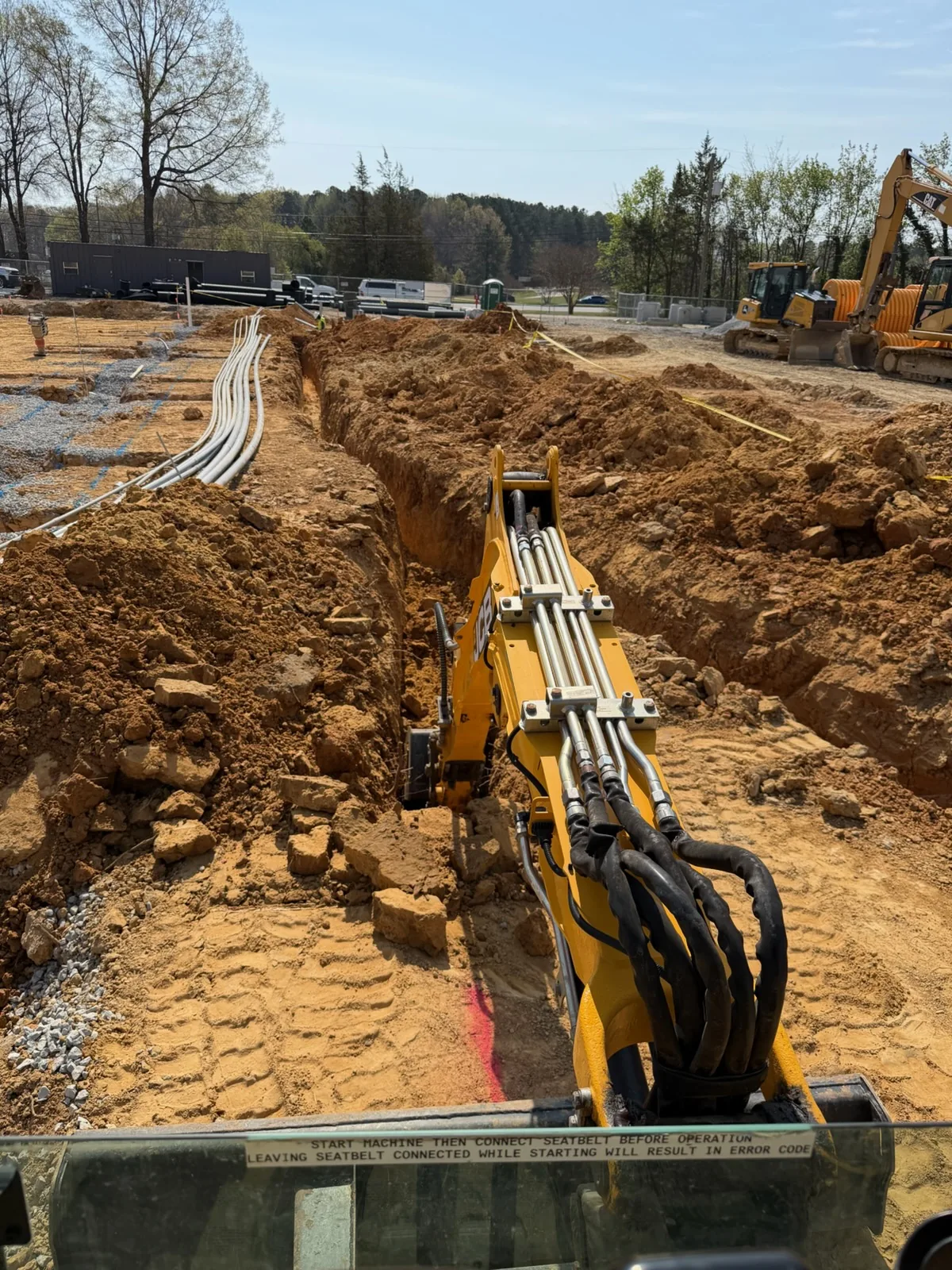 Open trench with banks of underground electrical conduit run across a job site